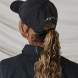 Person wearing a black cap with text, facing away from the camera.