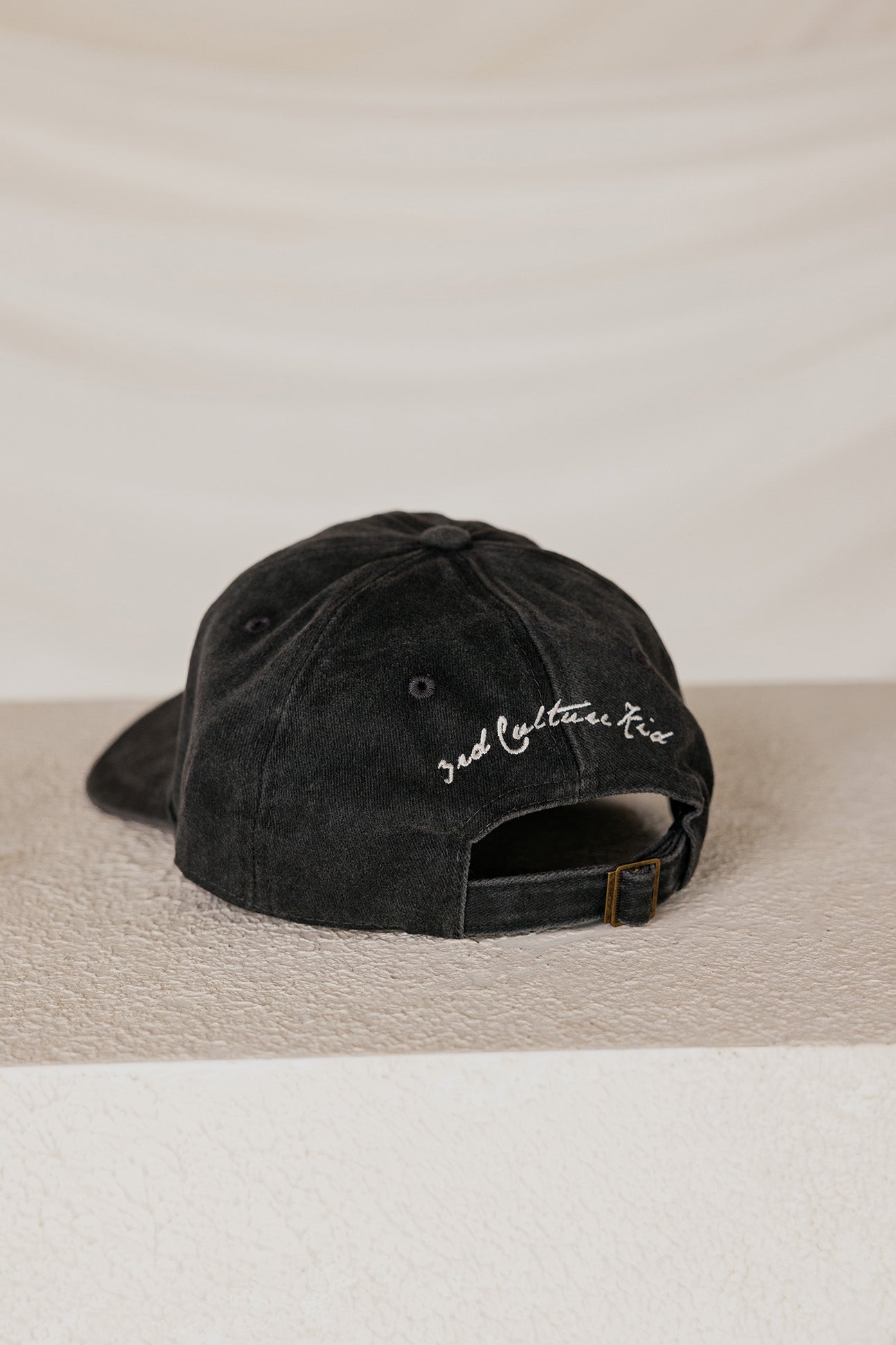 Black cap with text "3rd culture kid" on a beige surface