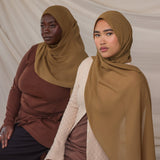 Two women wearing brown chiffon hijabs against a plain background