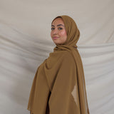 Woman wearing a brown chiffon hijab and outfit against a plain background