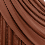 Close-up of draped brown fabric with soft folds and a slightly textured surface, shown against a small white background.