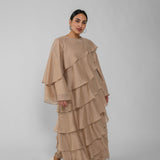 Woman wearing a beige layered dress on a gray background