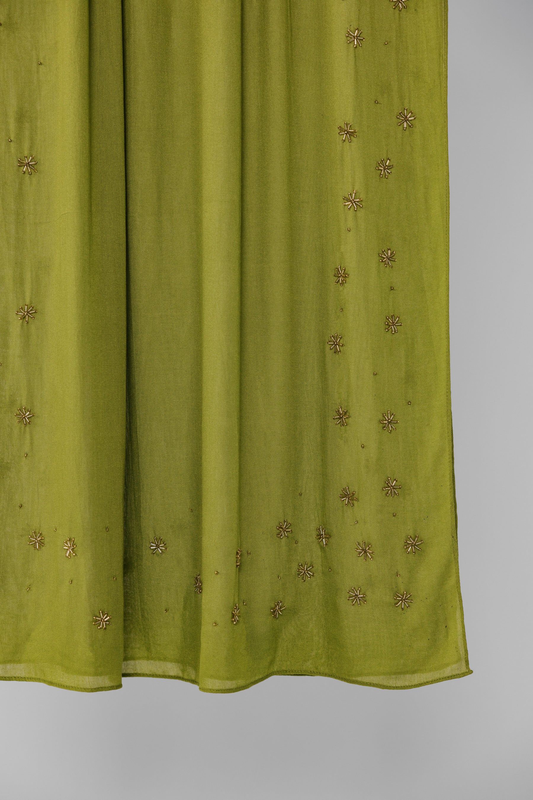 Green fabric with gold embroidery on a white background