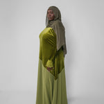 Woman wearing a green dress and headscarf against a white background