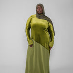 Woman wearing a green dress and hijab on a white background