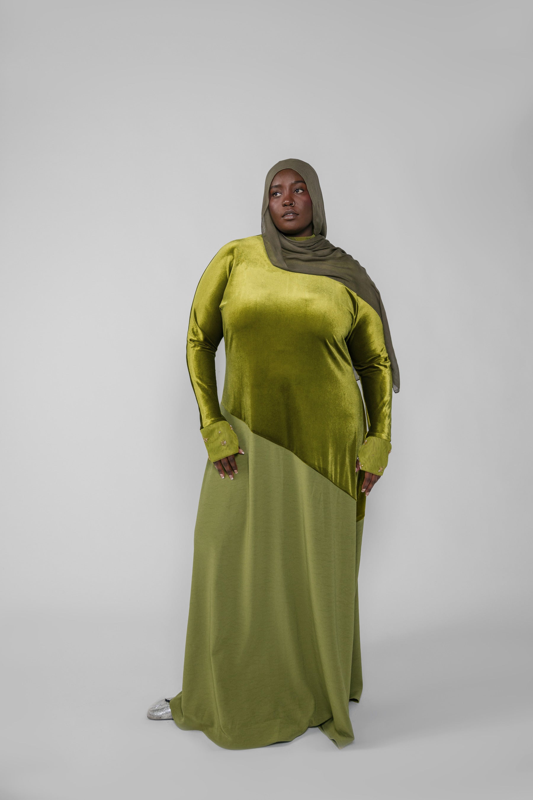 Woman wearing a green dress and hijab on a white background