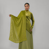 Woman wearing a green outfit with a matching scarf against a gray background