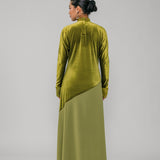Person wearing a green velvet outfit with a long skirt on a gray background