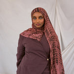 Woman wearing a red clay ripple print hijab and jacket against a white background