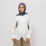 Woman wearing a white long-sleeve top and beige pants with a gray hijab on a white background