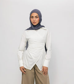 Woman wearing a white long-sleeve top and beige pants with a gray hijab on a white background