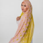 Woman wearing a pink and yellow polka dot hijab on a white background