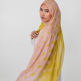 Woman wearing a pink and yellow polka dot hijab on a white background