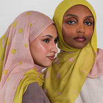 Two women wearing hijabs with a citrine polka dot pattern on a white background