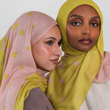 Two women wearing hijabs with a citrine polka dot pattern on a white background
