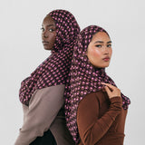 Two women wearing patterned hijabs against a white background