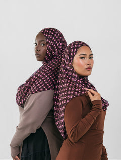 Two women wearing patterned hijabs against a white background