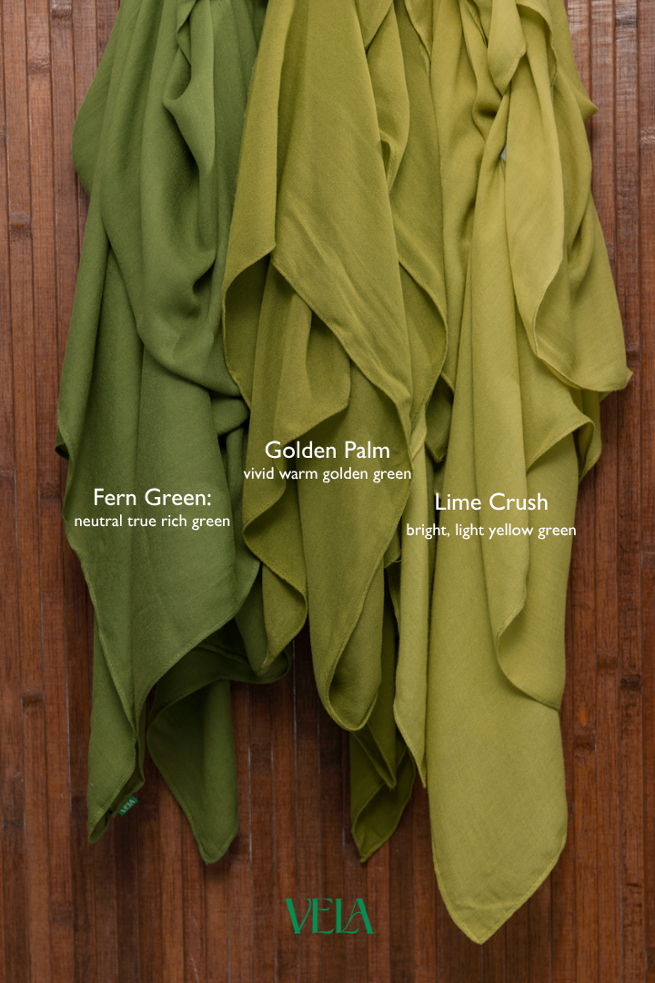 Three green scarves labeled 'Fern Green',  'Lime Crush', and 'Lime Crush' on a wooden background with Vela branding.