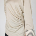 Beige long-sleeve top with striped cuffs on a white background