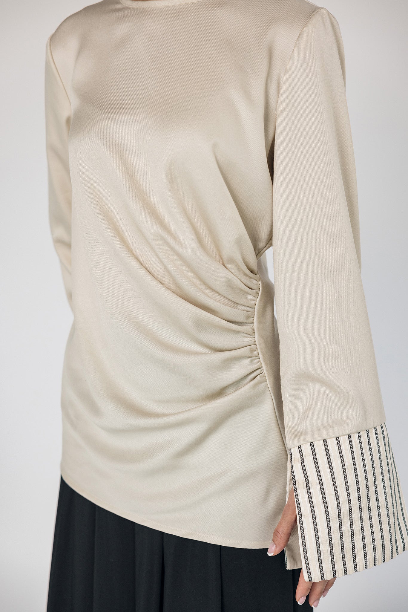 Beige long-sleeve top with striped cuffs on a white background