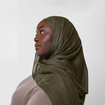 Woman wearing an olive hijab against a white background