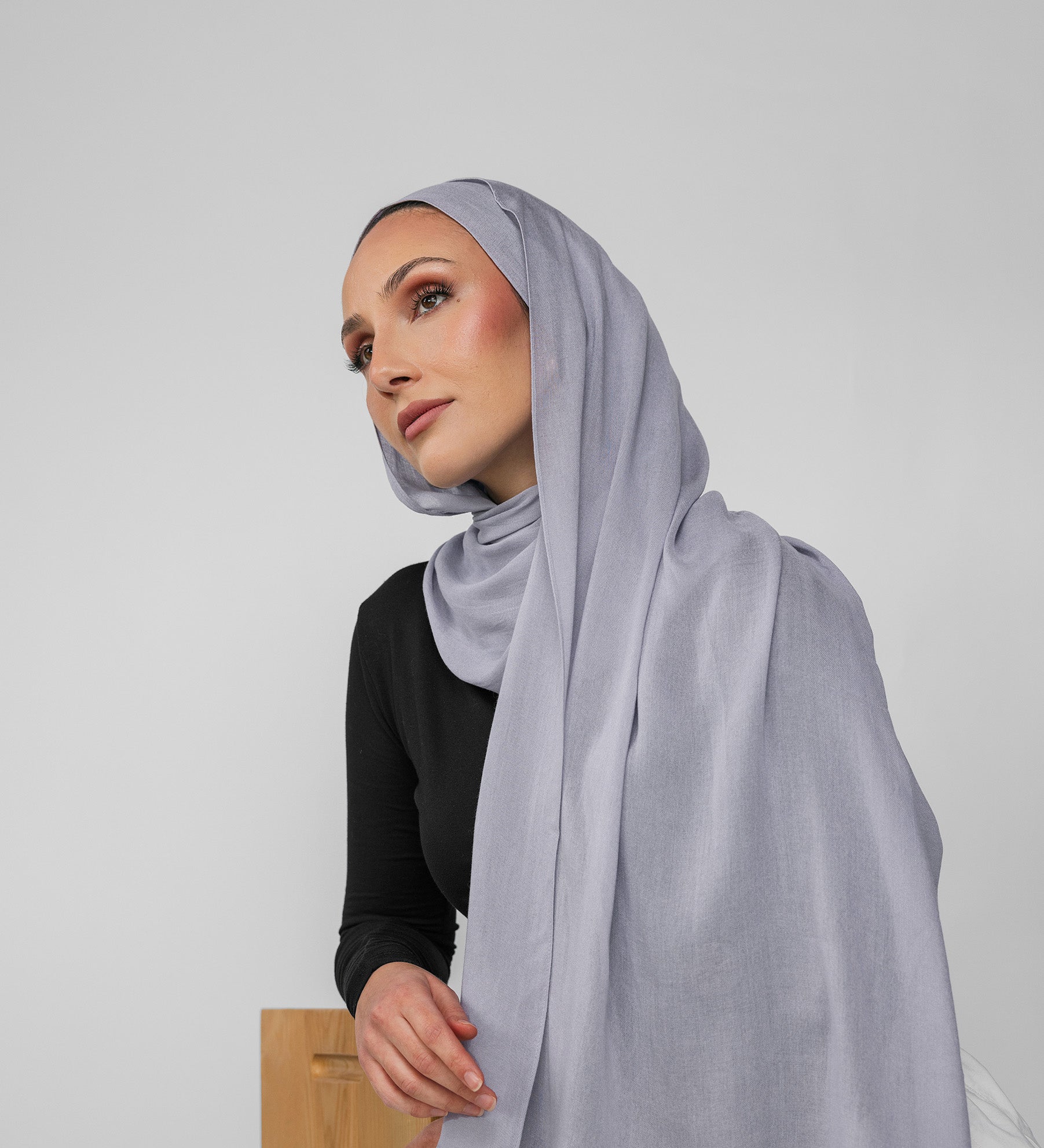 Woman wearing a light blue-gray hijab against a plain background