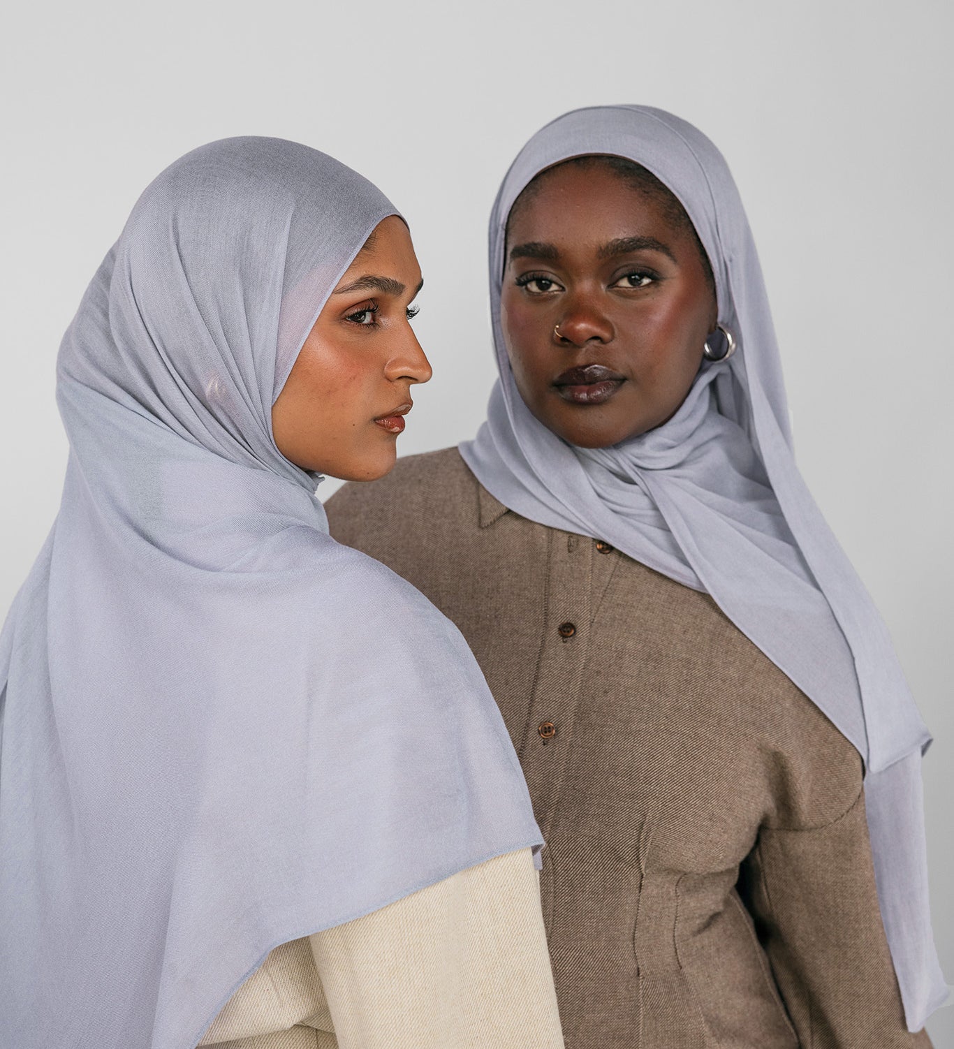Two women wearing light blue hijabs against a white background