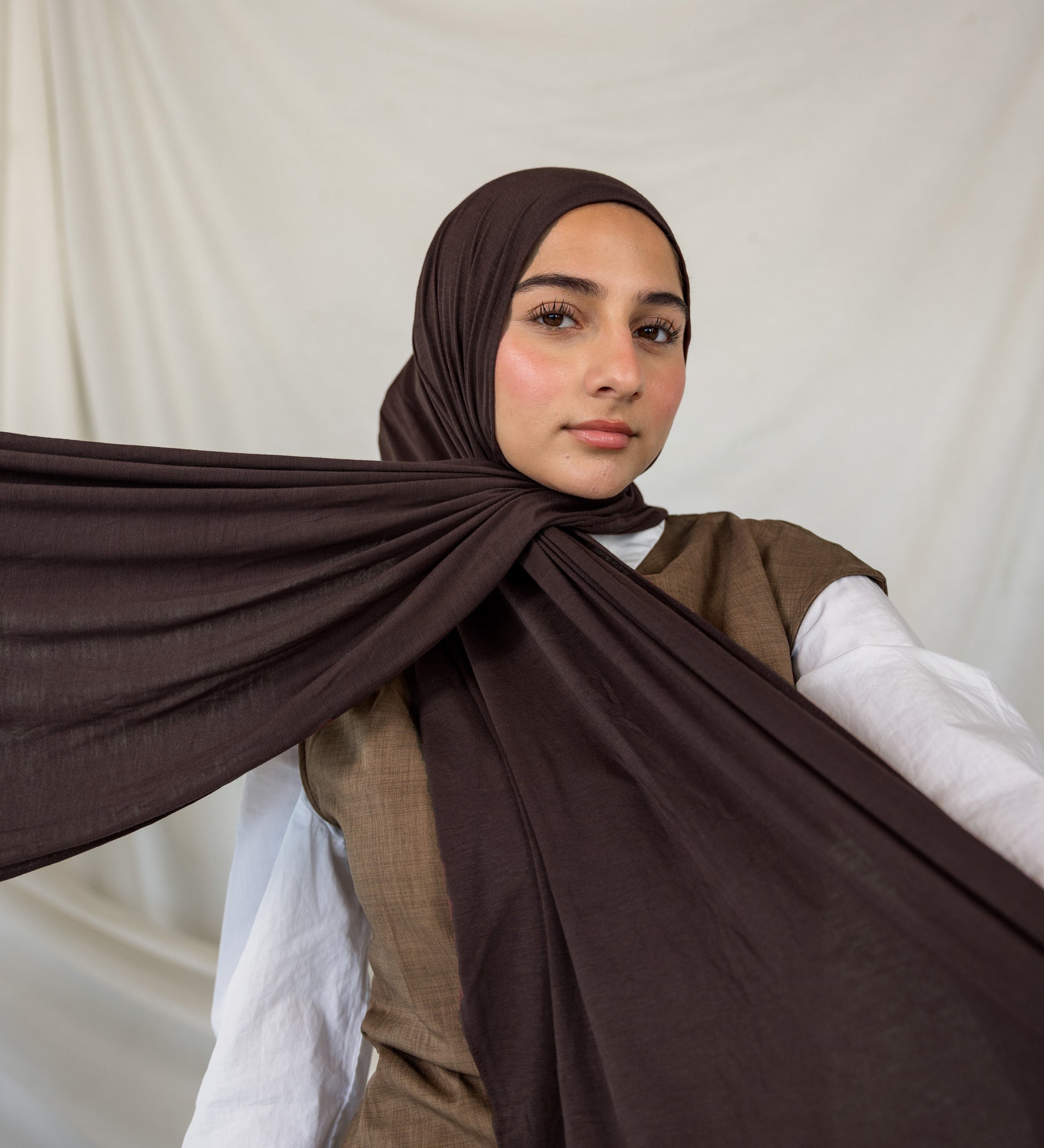 Woman wearing a brown hijab with a white background