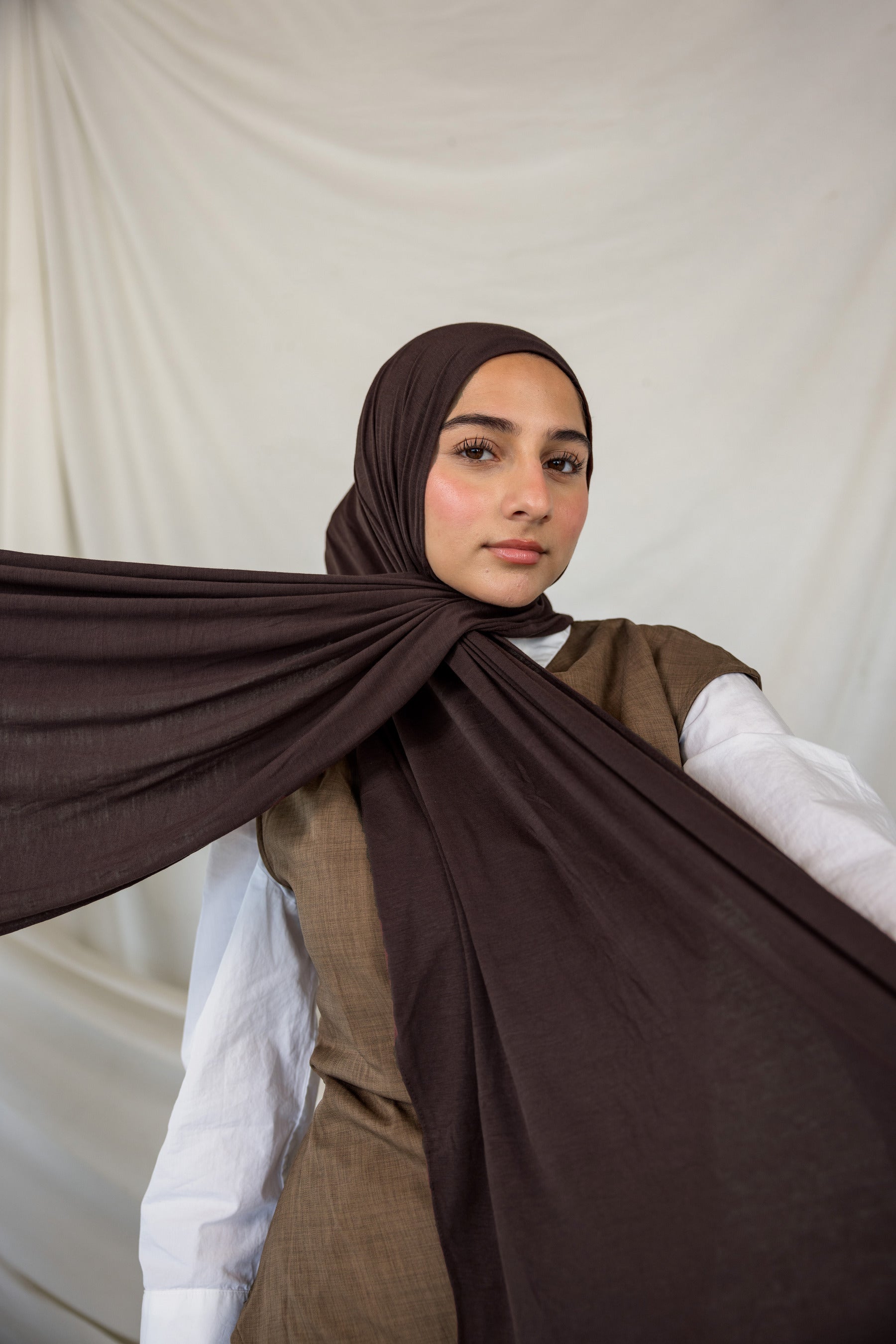 Woman wearing a brown hijab with a white background