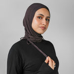 Woman wearing a black hijab against a gray background