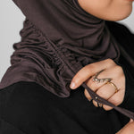 Person wearing a brown hijab with a neutral background