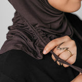 Person wearing a brown hijab with a neutral background