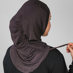 Person wearing a dark hijab with a plain background