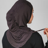 Person wearing a dark hijab with a plain background