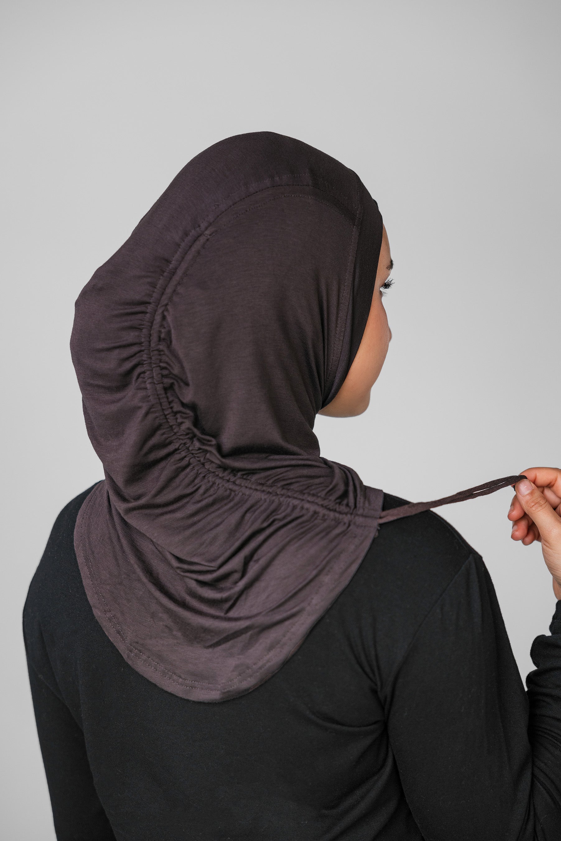 Person wearing a dark hijab with a plain background