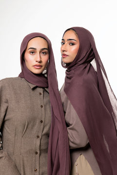 Two women modeling matching plum-colored hijabs and coordinated taupe button-front tops against a plain light gray studio background.