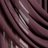 A close-up of draped sheer curtains in a deep plum purple color, showing the fabric's soft texture and light filtering through the folds.