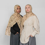 Two women wearing hijabs and long skirts against a plain background