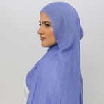 Woman wearing a light blue hijab against a white background