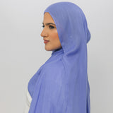Woman wearing a light blue hijab against a white background
