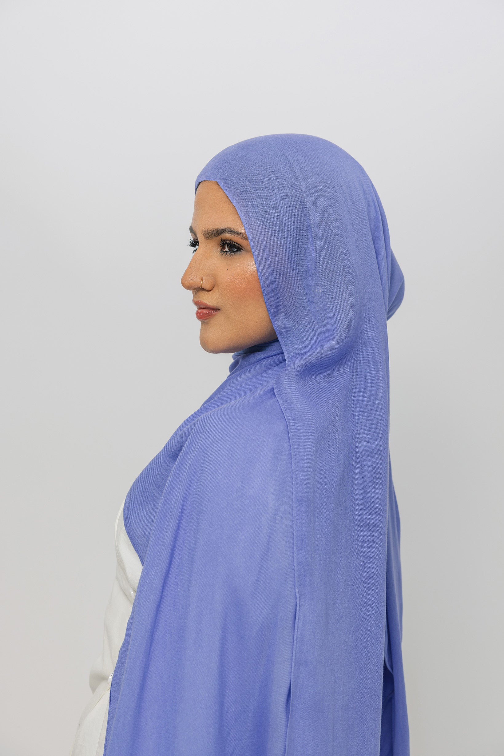 Woman wearing a light blue hijab against a white background