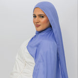 Woman wearing a light blue hijab against a white background