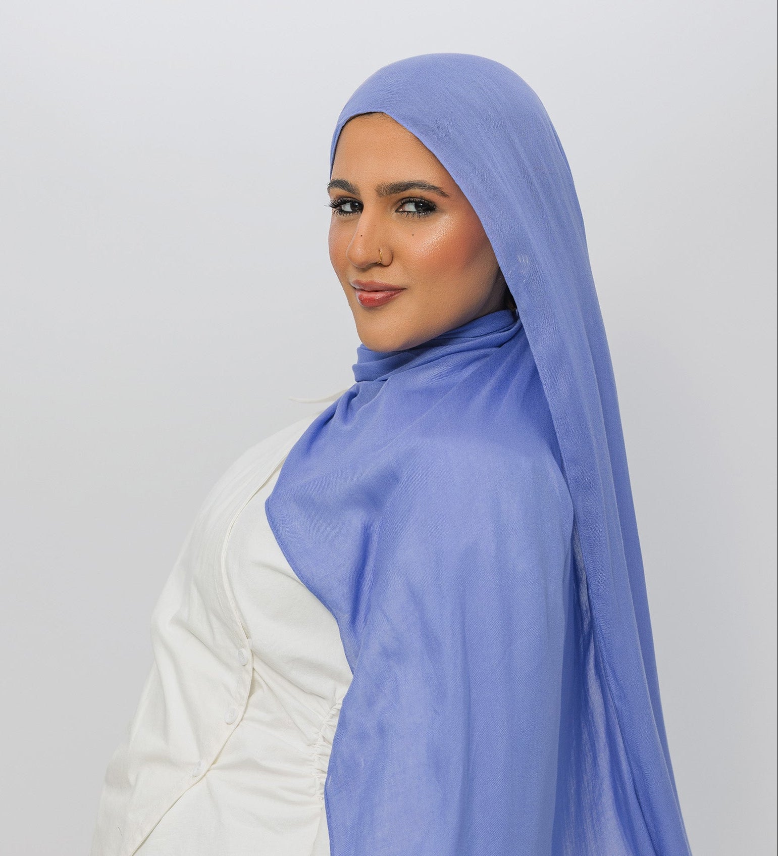 Woman wearing a light blue hijab against a white background