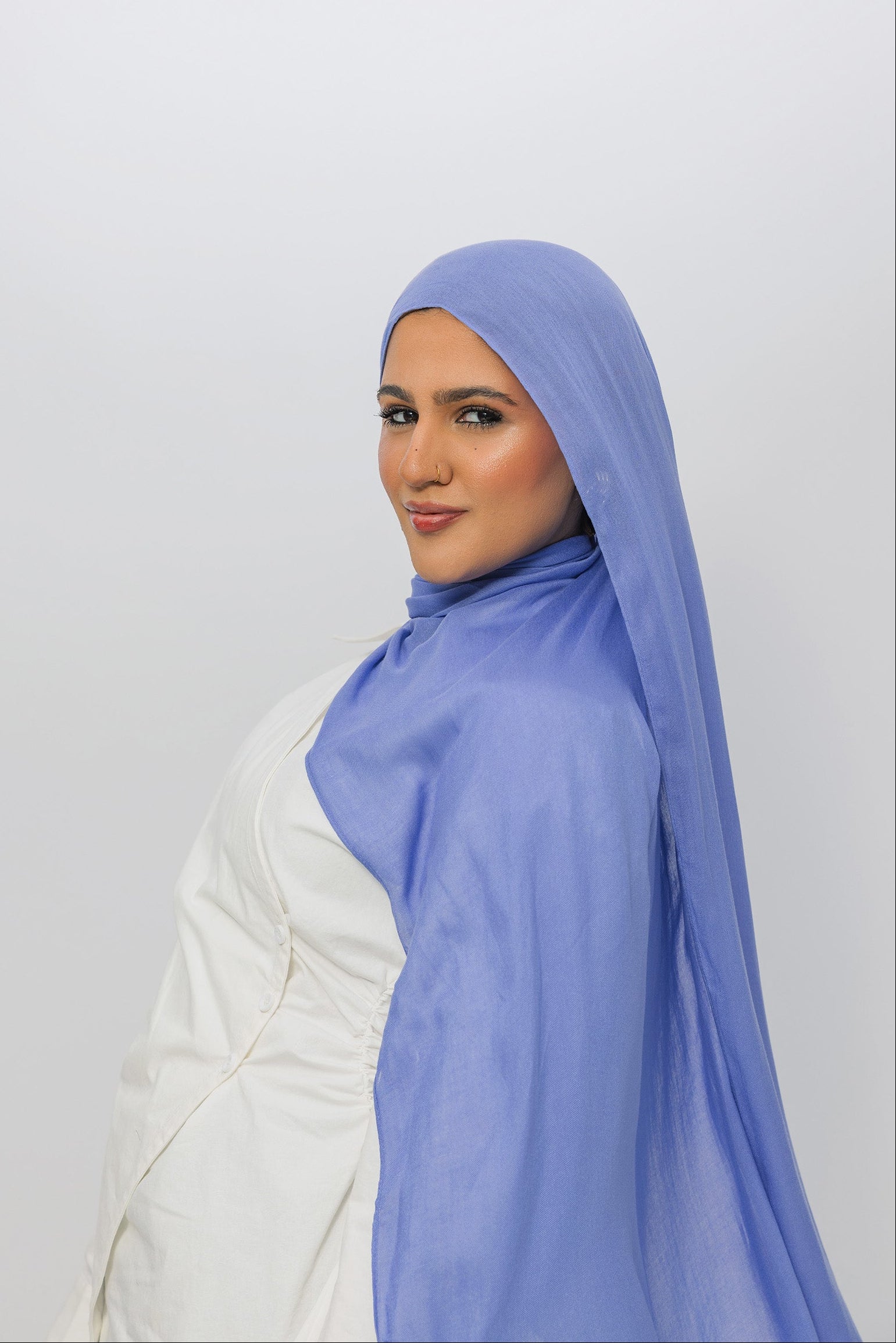 Woman wearing a light blue hijab against a white background