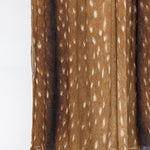 A close-up of a pleated brown fabric with a white spotted pattern, shown against a plain white background.