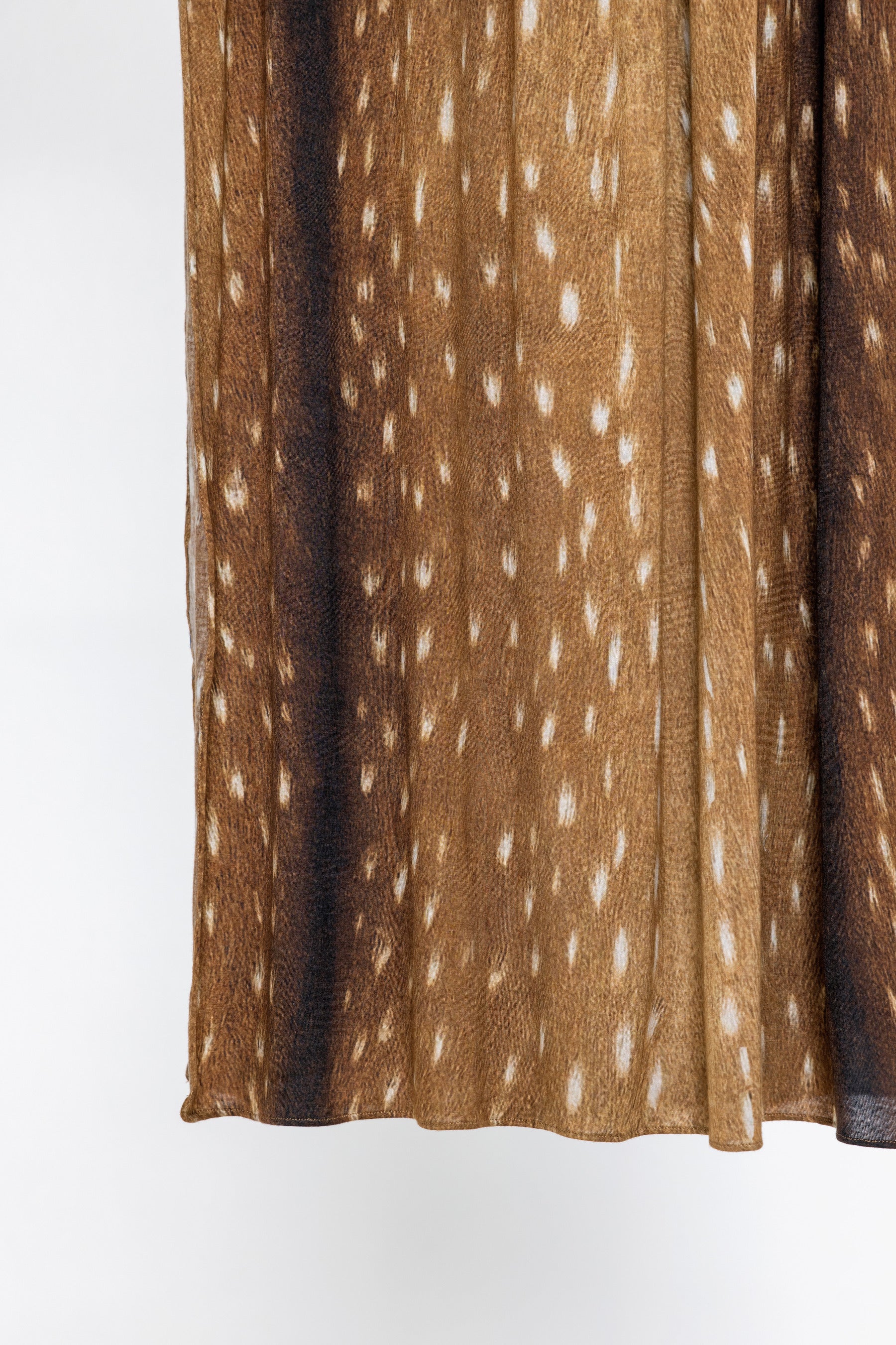 A close-up of a pleated brown fabric with a white spotted pattern, shown against a plain white background.
