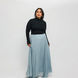 Woman wearing a black top and light blue skirt on a white background