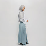 Woman wearing a light gray hijab and light blue skirt on a white background