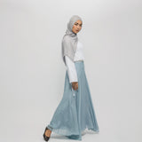 Woman wearing a gray hijab and light blue skirt on a white background