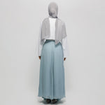 Person wearing a light gray hijab, white top, and light blue skirt on a white background